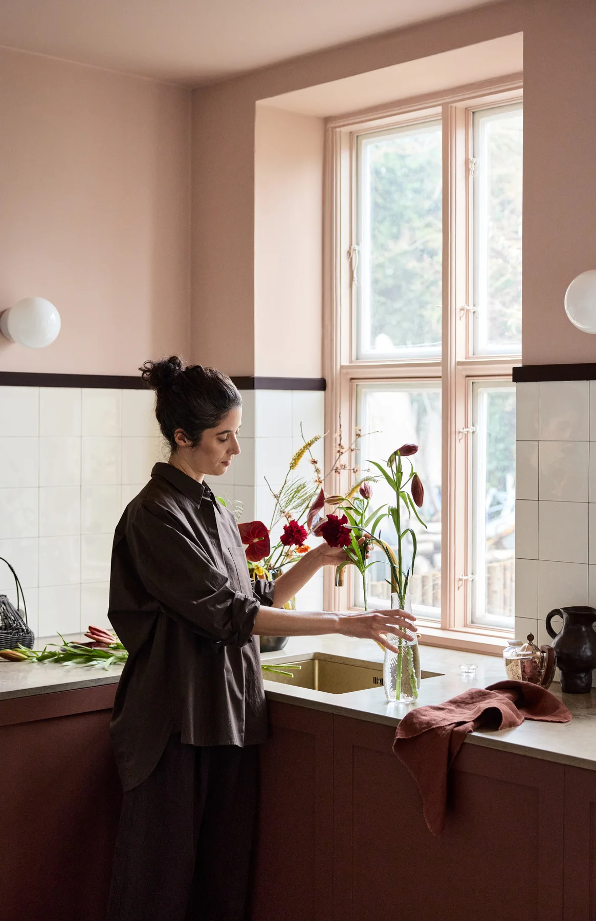 Bếp với tường hồng be, tủ đỏ trầm và chi tiết nâu sâu